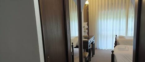 A hotel room with a bed, a desk, a chair, and a mirror.