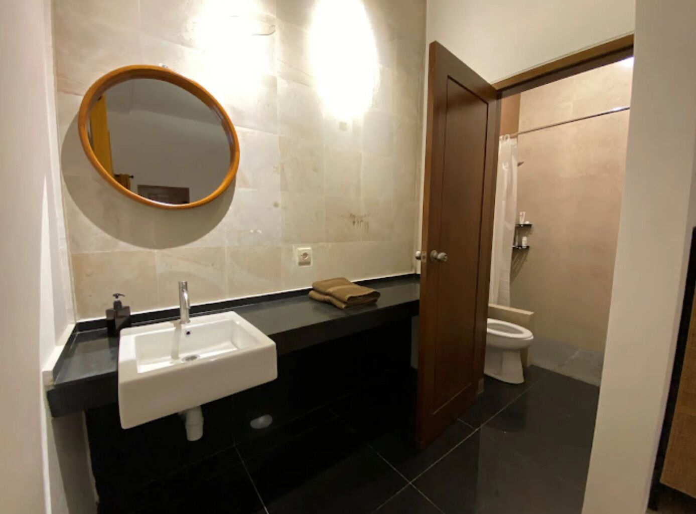 A bathroom with a white sink, a round mirror, and a toilet.