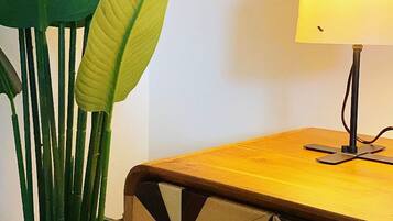 Una stanza con un tavolino in legno, una lampada e un vaso blu con foglie verdi.