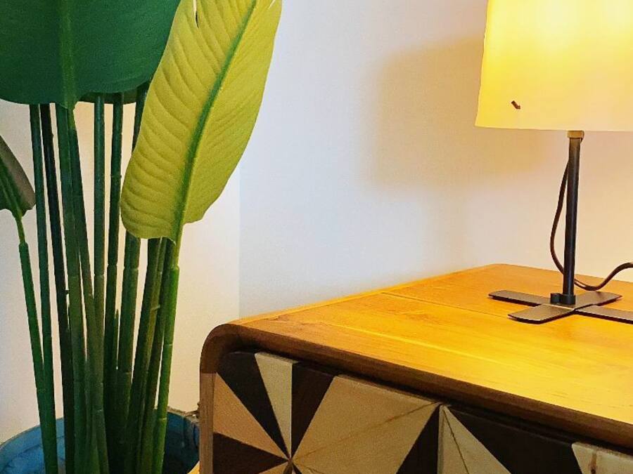 Una stanza con un tavolino in legno, una lampada e un vaso blu con foglie verdi.