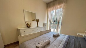 A bedroom with a bed, a dresser, a mirror, and a window with curtains. - [BGY/CITY] Comfortable apartment in the BORGO (Bergamo)