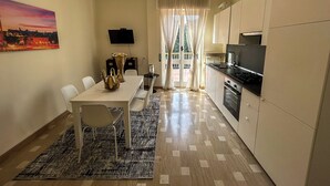A compact kitchen with a dining area, a flat-screen TV, and a view through the window. - [BGY/CITY] Comfortable apartment in the BORGO (Bergamo)