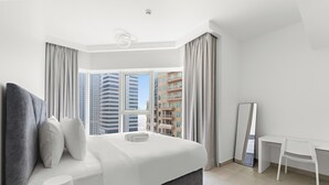 Una camera d'hotel moderna con un ampio letto, una scrivania e vista su edifici alti.