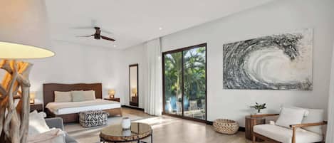 A modern hotel room with a large bed, a seating area with a round coffee table, and a large abstract painting on the wall.