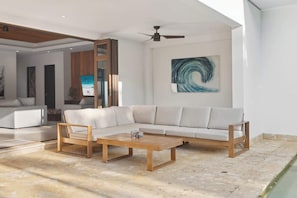 A modern living room with a sectional sofa, a wooden coffee table, and a ceiling fan.