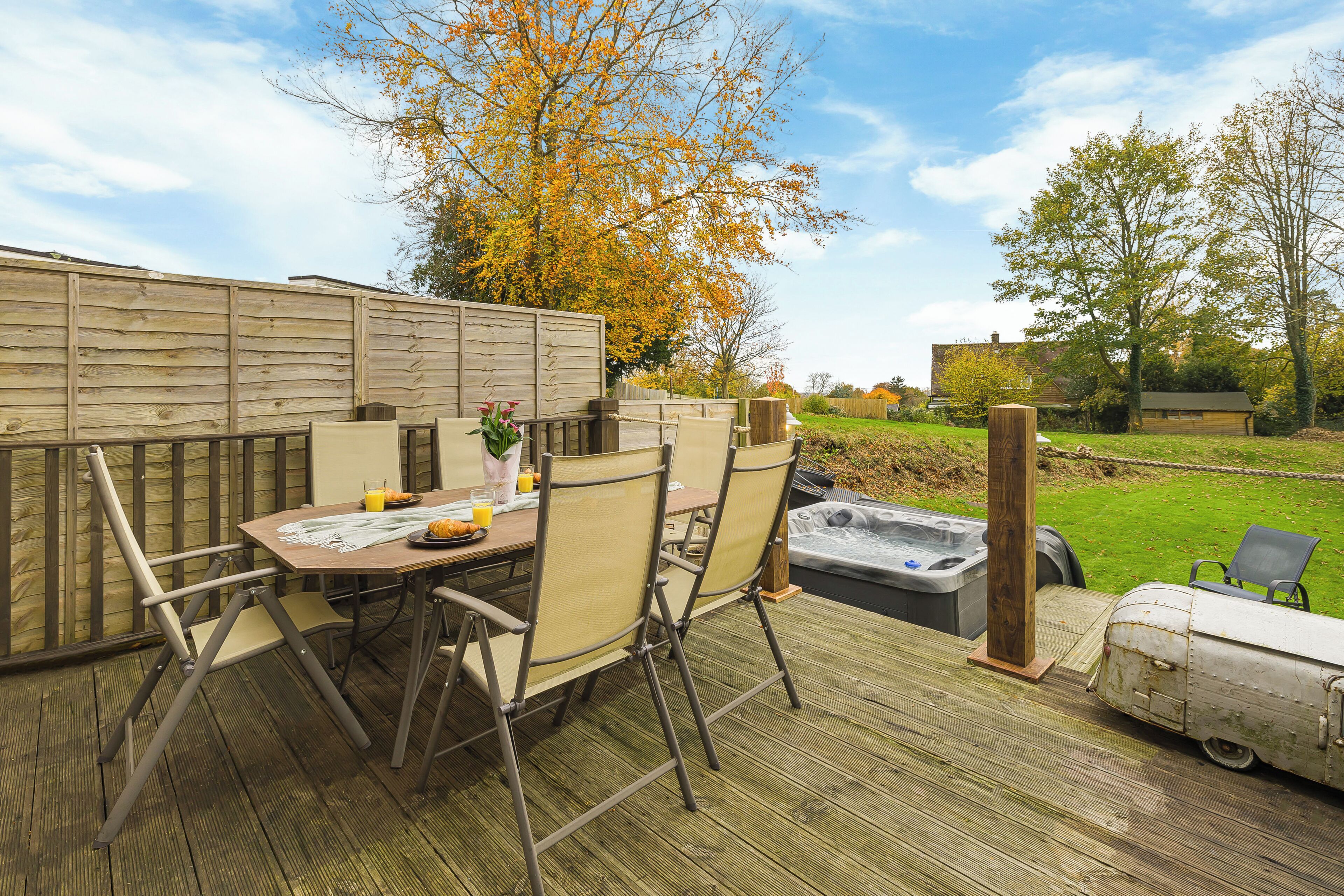 An outdoor patio with a table and chairs, a hot tub, and a wooden deck.