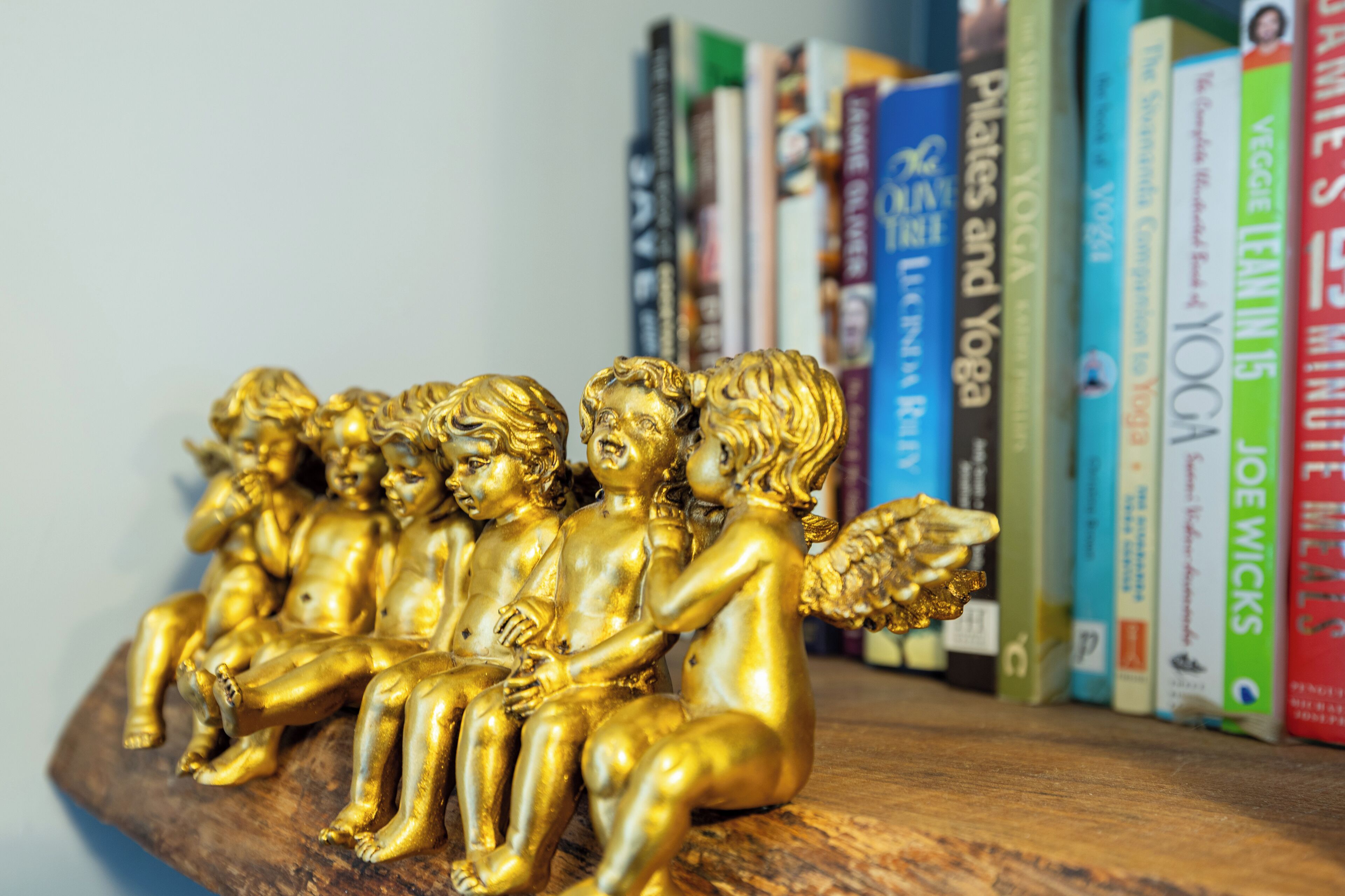 Ein Holzregal mit einer Sammlung von Büchern und einer goldenen Engel-Figur.