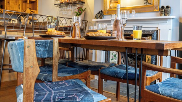 Un coin repas chaleureux avec des chaises en bois et une table dressée pour le petit-déjeuner.