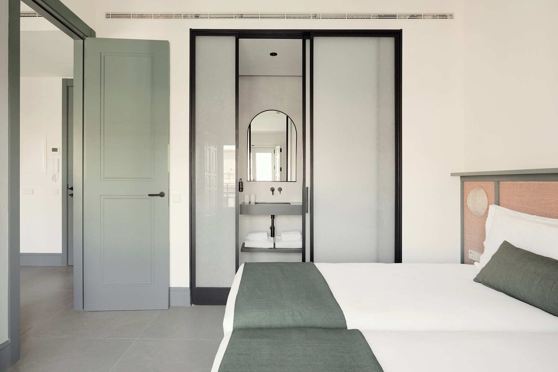 A hotel room with a bed, a bathroom with a mirror and sink, and a closet with sliding doors.