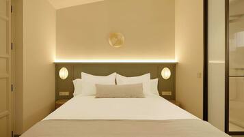 Een hotelkamer met een groot bed, een hoofdeinde met ingebouwde verlichting en uitzicht op een schuifdeur.