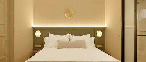 A hotel room with a large bed, a headboard with integrated lighting, and a view of a sliding door.