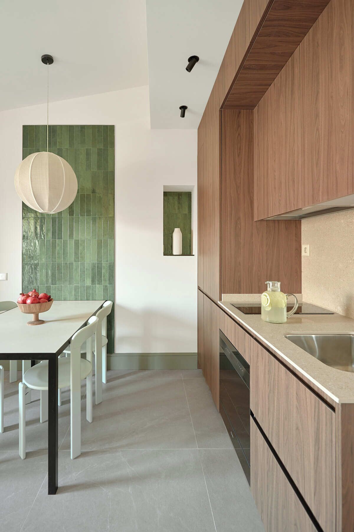 Een moderne keuken met een houten kastje, een spoelbak en een eethoek met een tafel en stoelen.