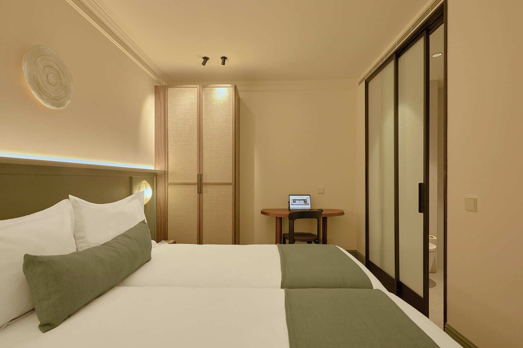 Una habitación de hotel con una cama, una mesita con un ordenador portátil y un armario corredero.
