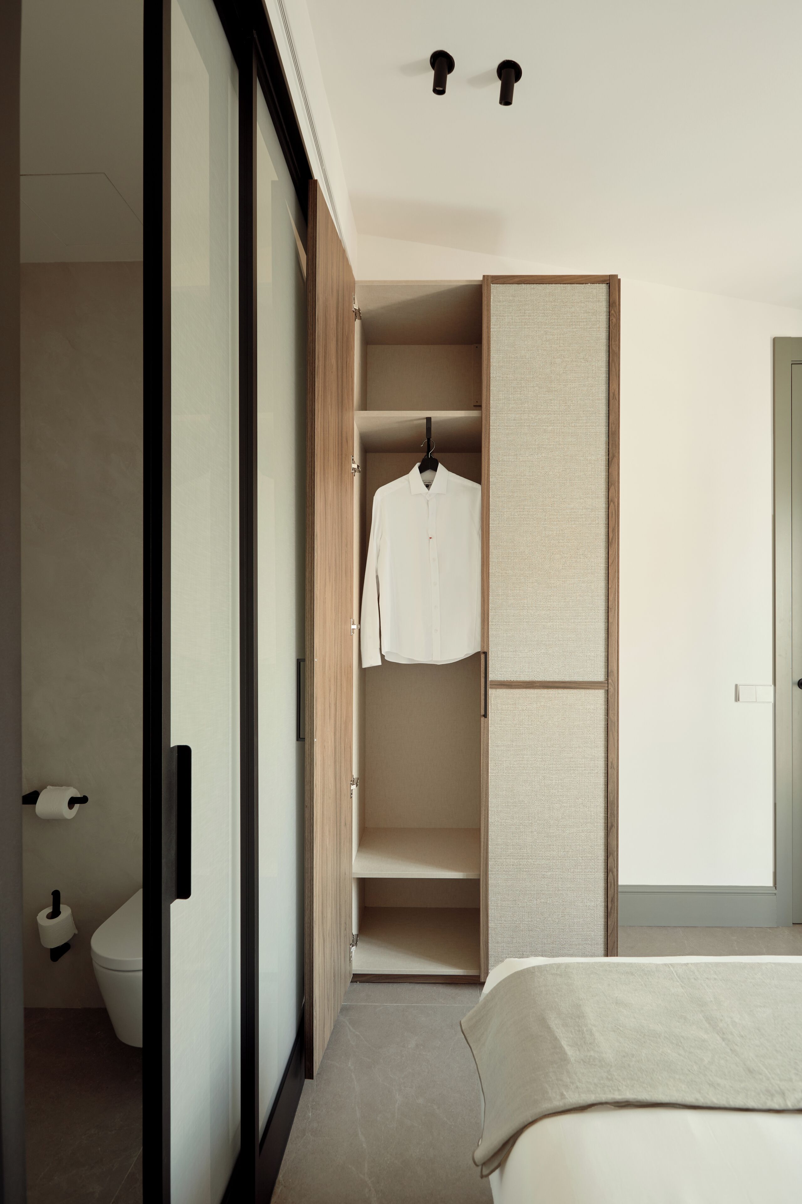 Une chambre moderne comprenant un lit, une armoire et une salle de bain avec des toilettes et des serviettes.