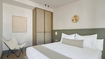A neatly arranged hotel room with a large bed, a chair, a wardrobe, and a wall-mounted artwork.