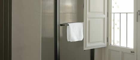 Un baño con inodoro, toallero y puerta que da a un balcón.