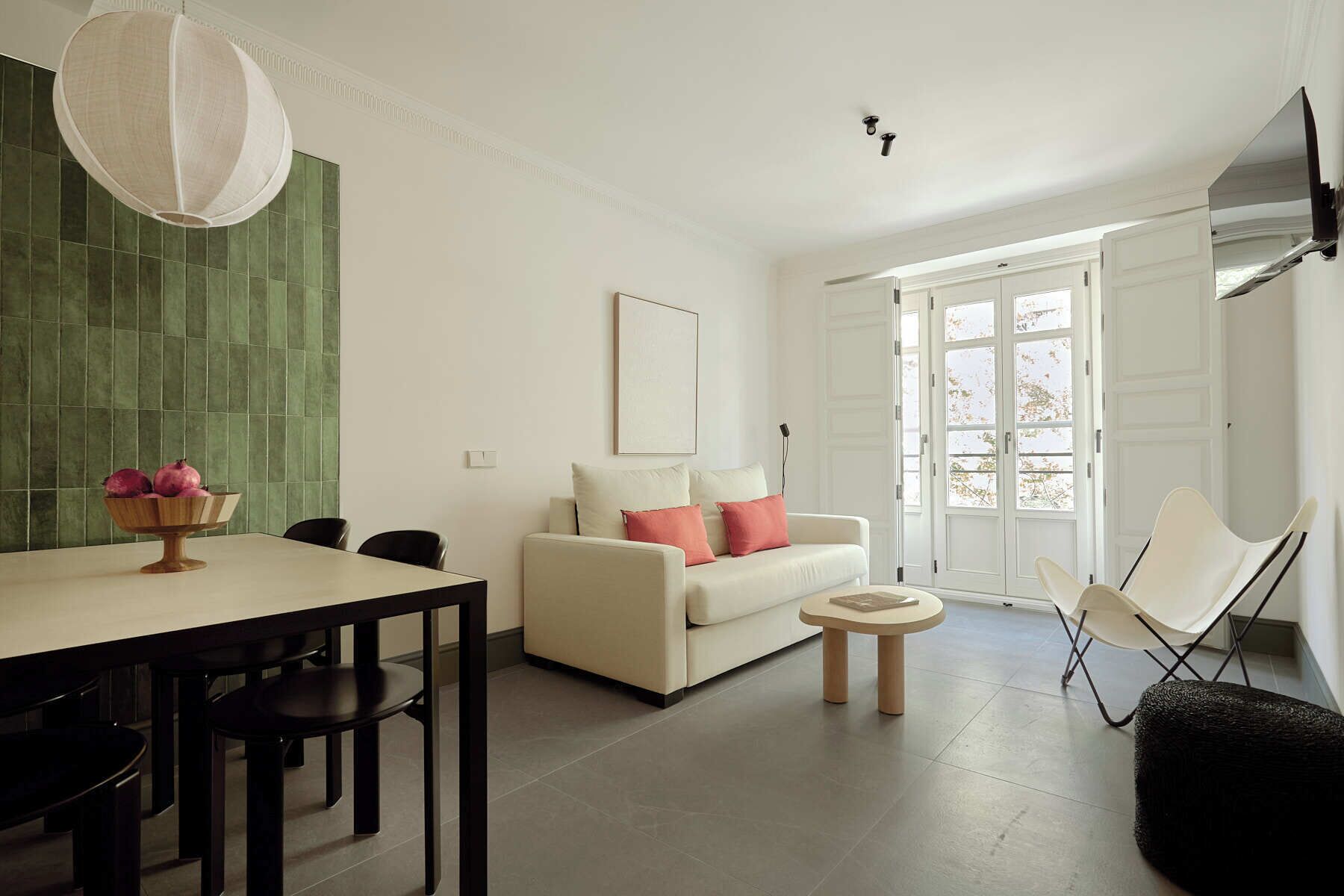 A modern living room with a dining area, a sofa, a coffee table, and a TV mounted on the wall.
