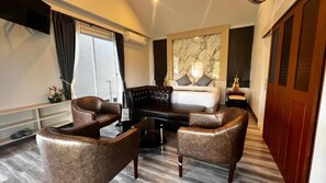 A hotel room with a bed, two leather armchairs, a small table, a marble artwork on the wall, and a wooden door. - Le Best Pool Villa Chiangmai (San Sai)