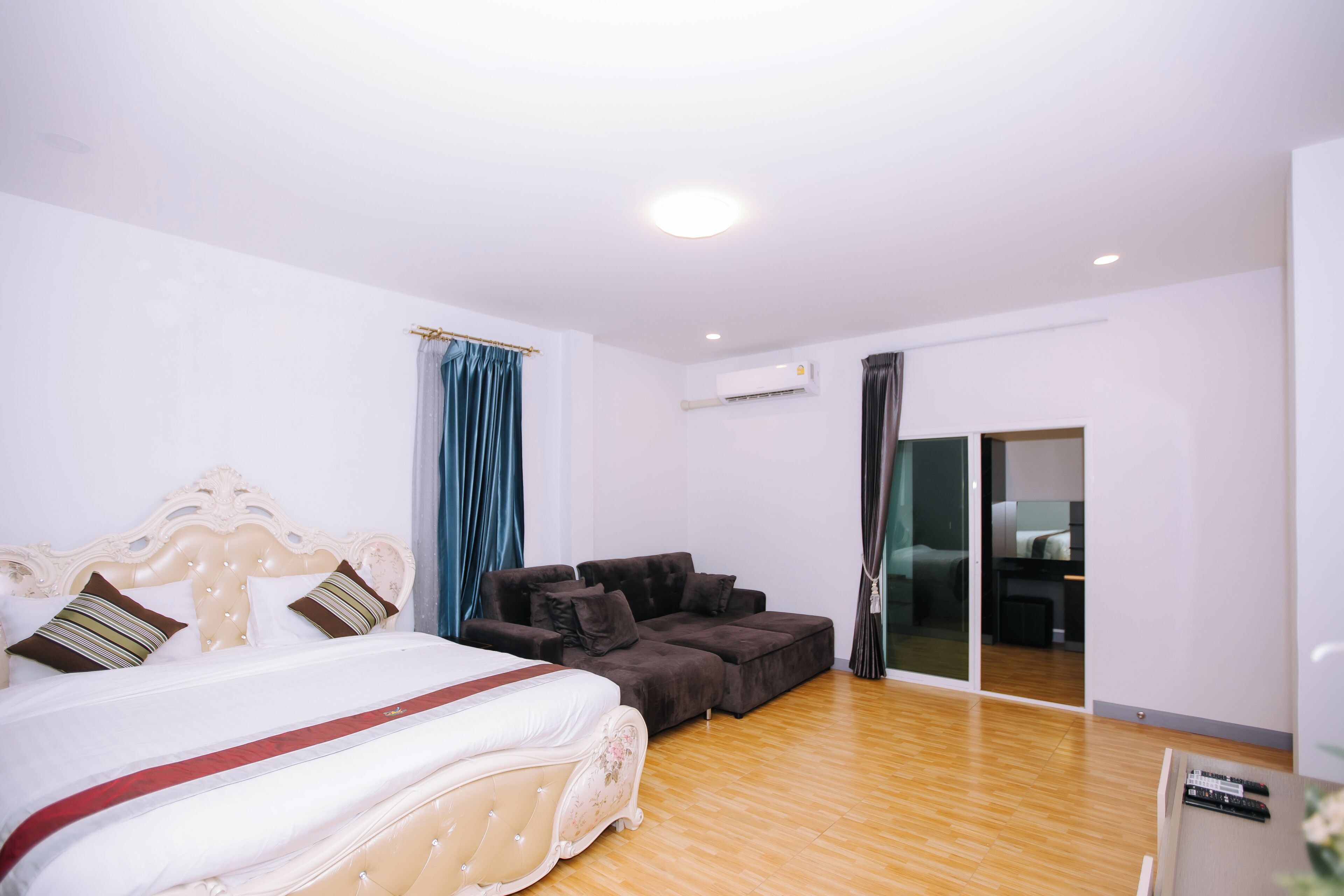 A bedroom with a large bed, a sofa, and a sliding glass door to a balcony.