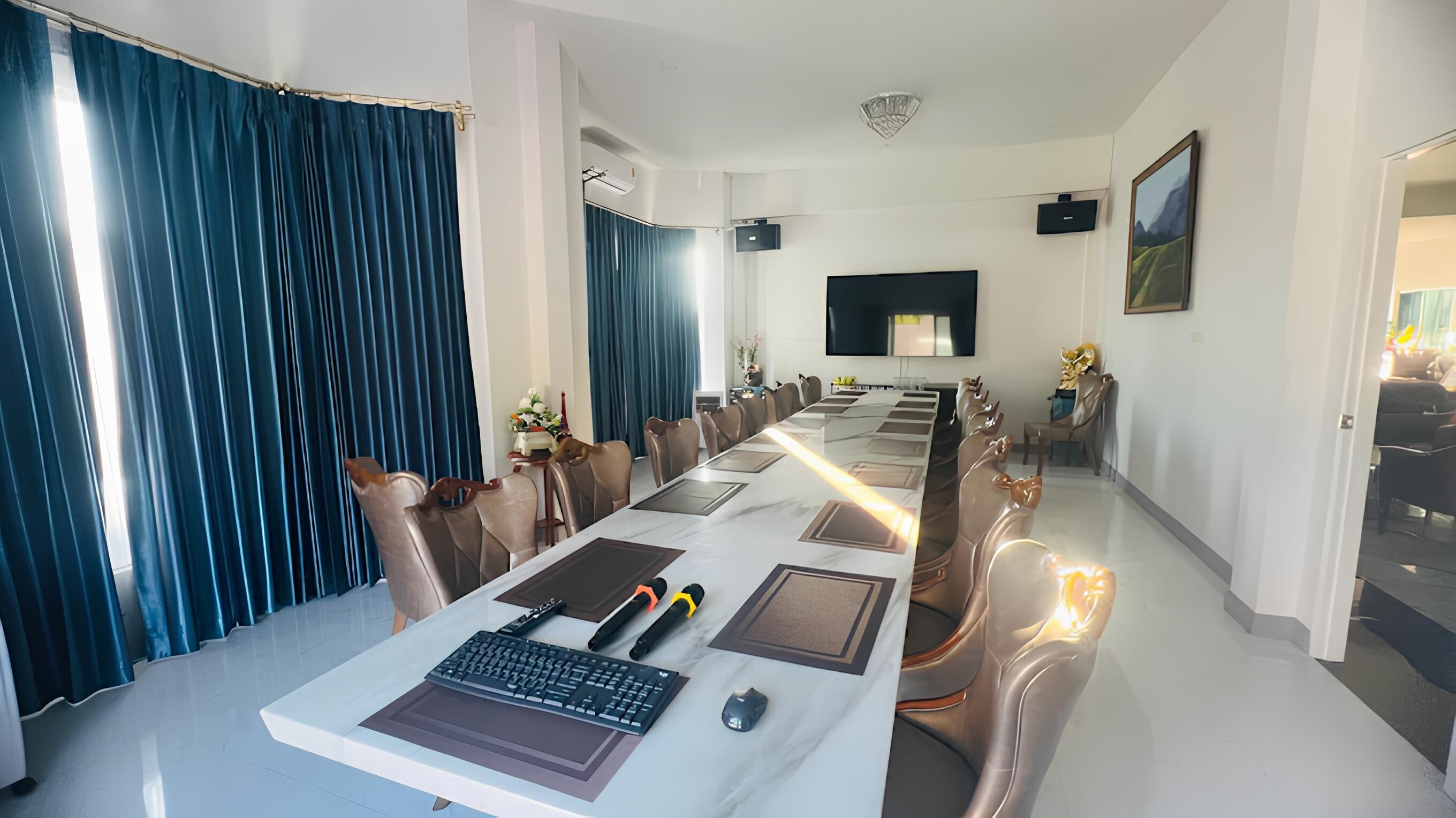 Una sala de conferencias moderna con una mesa larga, sillas, un televisor y un cuadro en la pared.