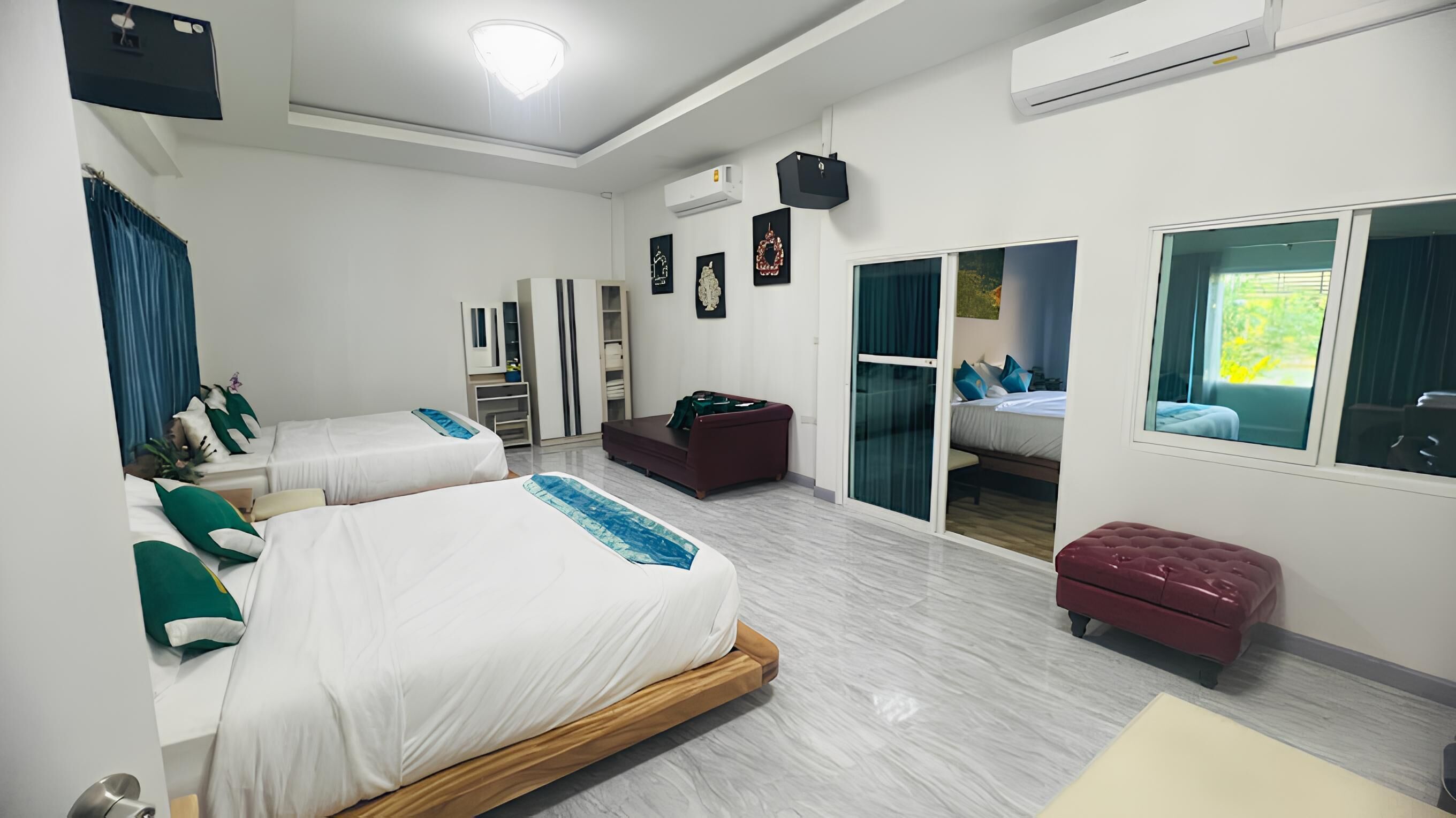 A modern hotel room with two beds, a seating area, a wardrobe, and a sliding door to a balcony.