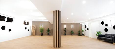A spacious, modern interior with a wooden floor, a central column, and a black leather sofa.