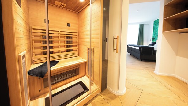 A sauna with wooden walls and a glass door, a bench, and a towel rack.