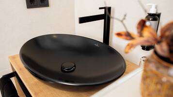 A black vessel sink on a wooden countertop with a black faucet and a soap dispenser.