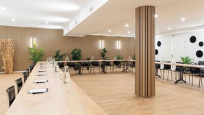 A modern conference room with a long table, chairs, and plants.