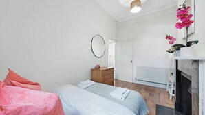 Quarto com cama, penteadeira, espelho, radiador e lareira.