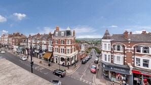 A street view of a town with historic buildings, shops, and parked cars.
