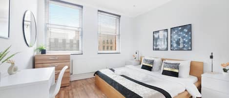 A modern bedroom with a bed, bedside tables, a desk, and a chair.