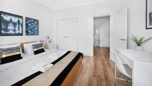 Ein modernes Hotelzimmer mit einem großen Bett, einem Schreibtisch und Blick ins Badezimmer.