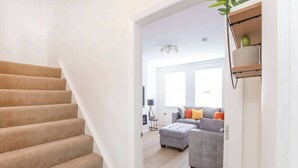 A staircase leading to a living area with a grey sofa and orange cushions.