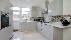 A modern kitchen with white cabinetry, a built-in oven, a microwave, and a gas stove.