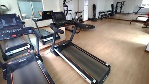 A gym with treadmills, a stationary bike, and a punching bag. - Lux Suites Vesta Gardens Apartments (Nairobi)