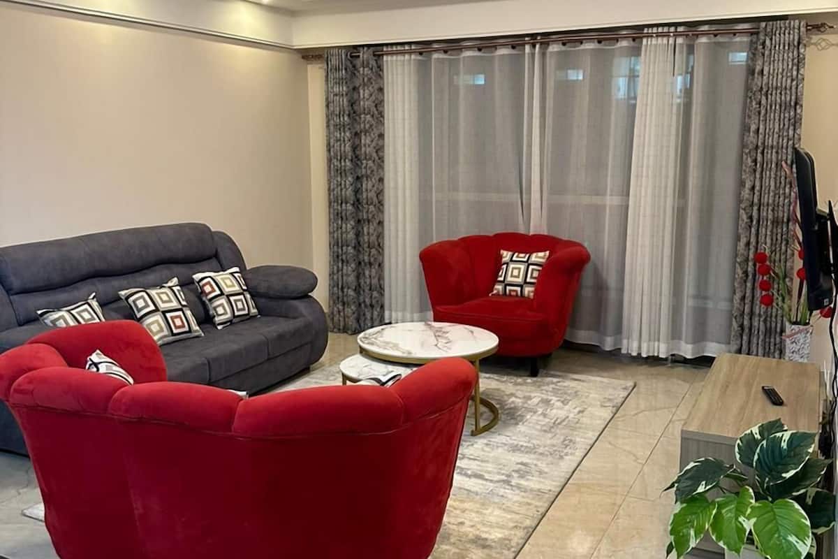 Ein modernes Wohnzimmer mit einem grauen Sofa, einem roten Sessel und einem kleinen runden Tisch.