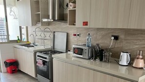A modern kitchen with a central island, stainless steel appliances, and a microwave. - Lux Suites Vesta Gardens Apartments (Nairobi)