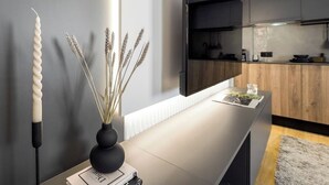 A modern kitchen with a built-in TV, a white countertop, and a vase with dried plants. - Aristotelian Virtues - Enkrateia (Thessaloniki)