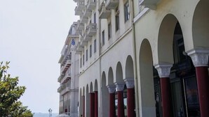 Ein mehrstöckiges Gebäude mit Balkonen, Bogenfenstern und einer blauen Flagge.