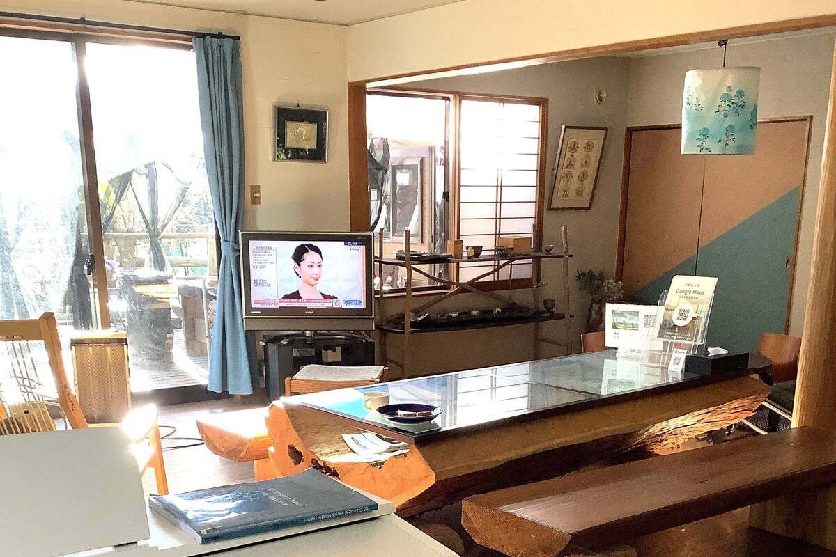 Ein modernes Wohnzimmer mit einer Holzbänkchen, einem Glastisch und einem Fernseher.