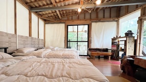 Ein Schlafzimmer mit zwei Betten, Holzbalken, einem großen Fenster und einer hölzernen Bank.