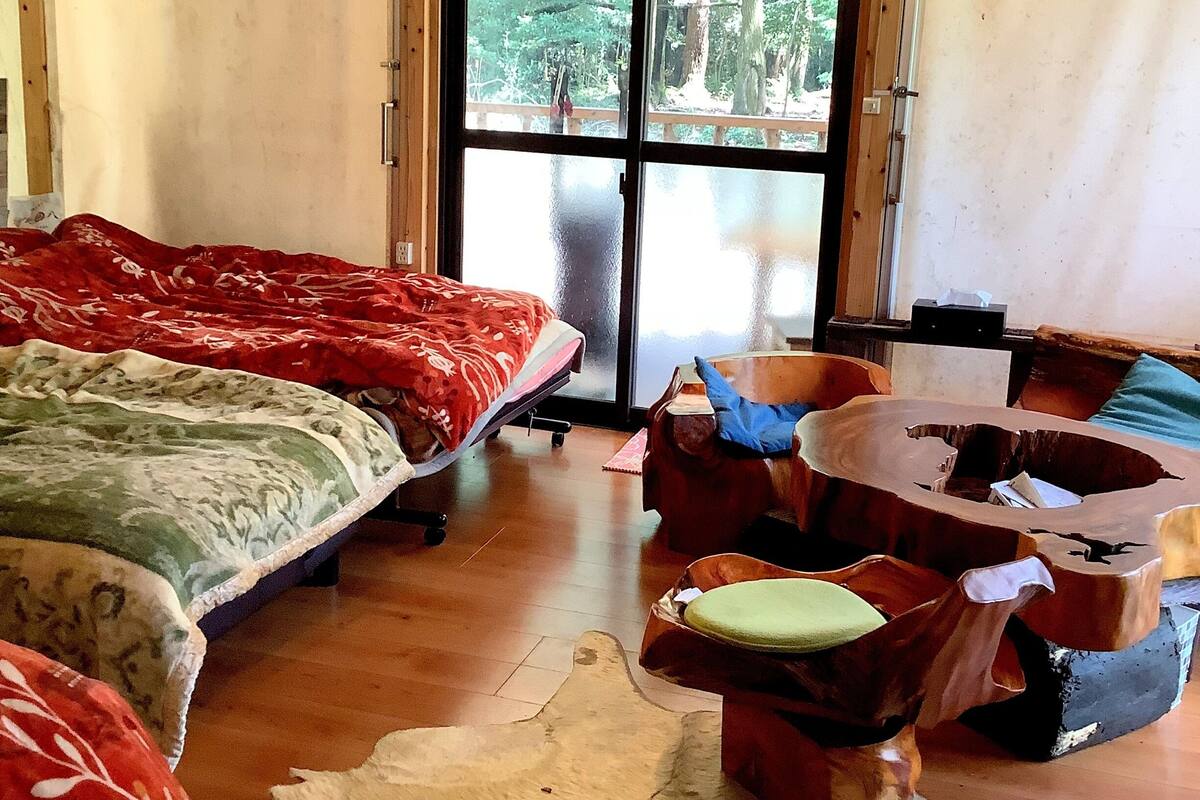 Ein Zimmer mit einem Bett, einem Holzstuhl, einem Teppich und einem großen Fenster.