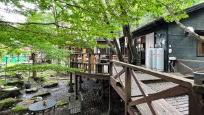 Eine Holzterrasse mit Blick auf ein Gebäude, umgeben von Bäumen und Felsen.