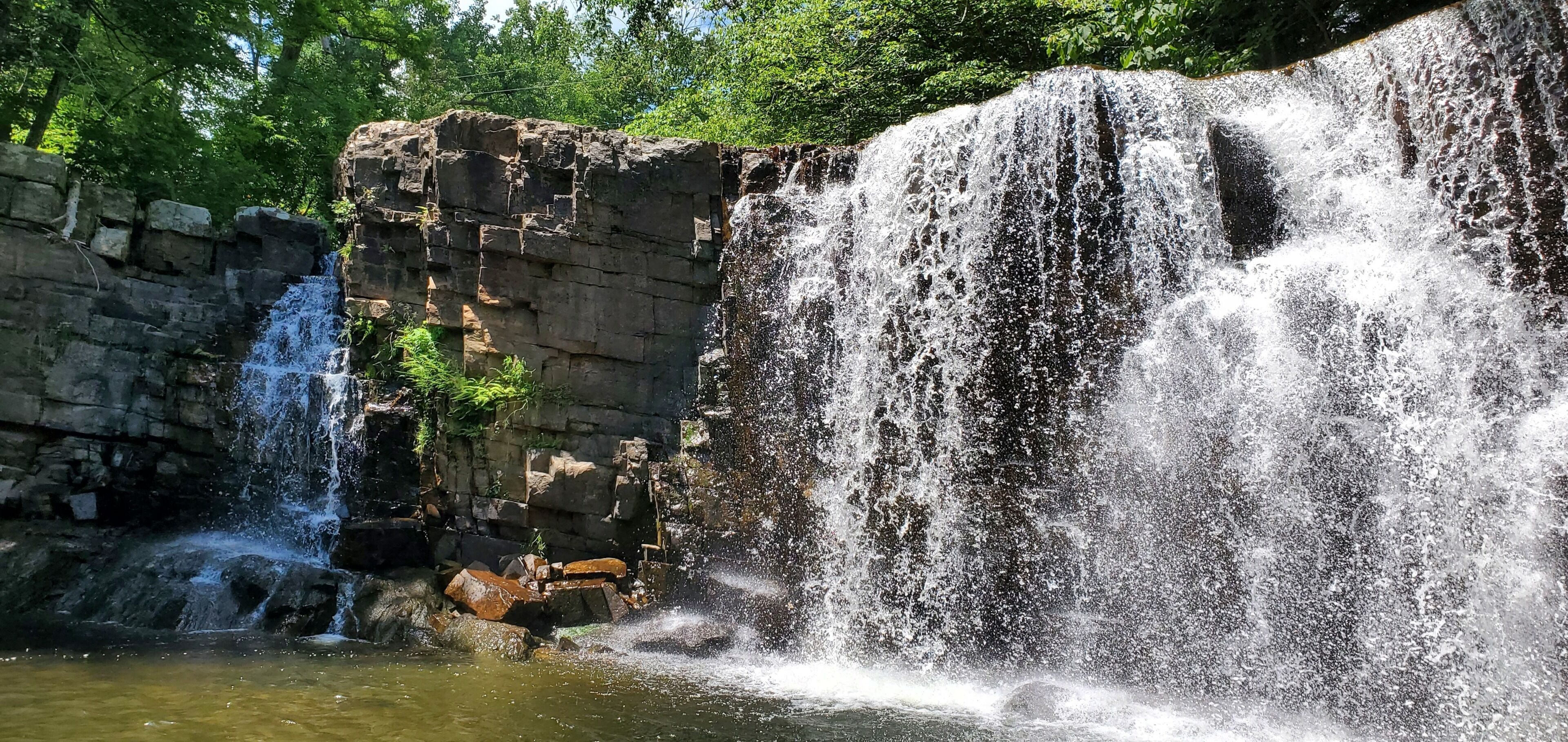 Una cascada se precipita sobre un acantilado rocoso hacia una poza.