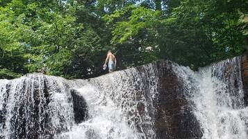 Una cascada con una persona de pie sobre un saliente rocoso.