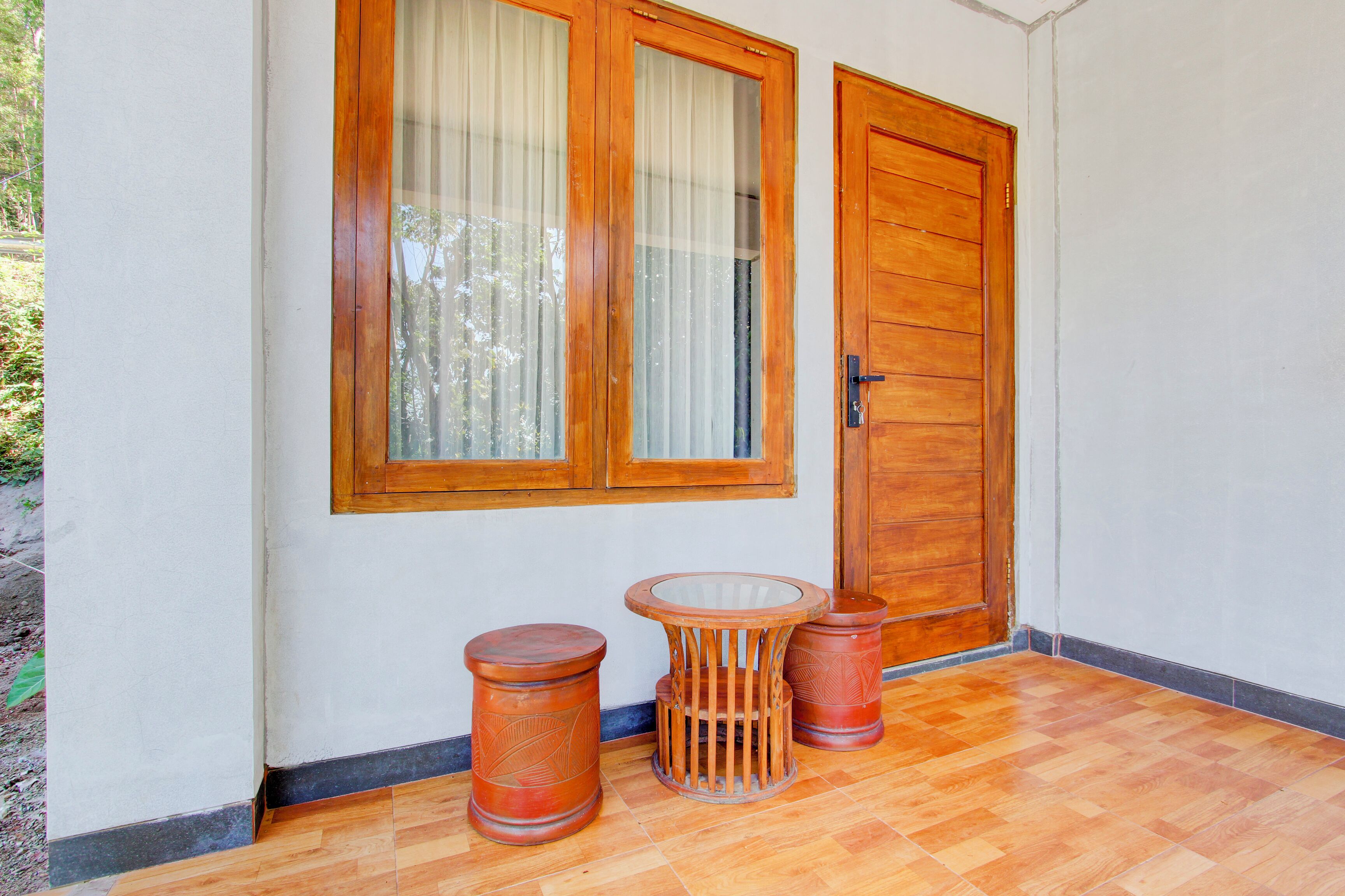 Una porta in legno con un vetro, un tavolino rotondo e due sgabelli cilindrici.