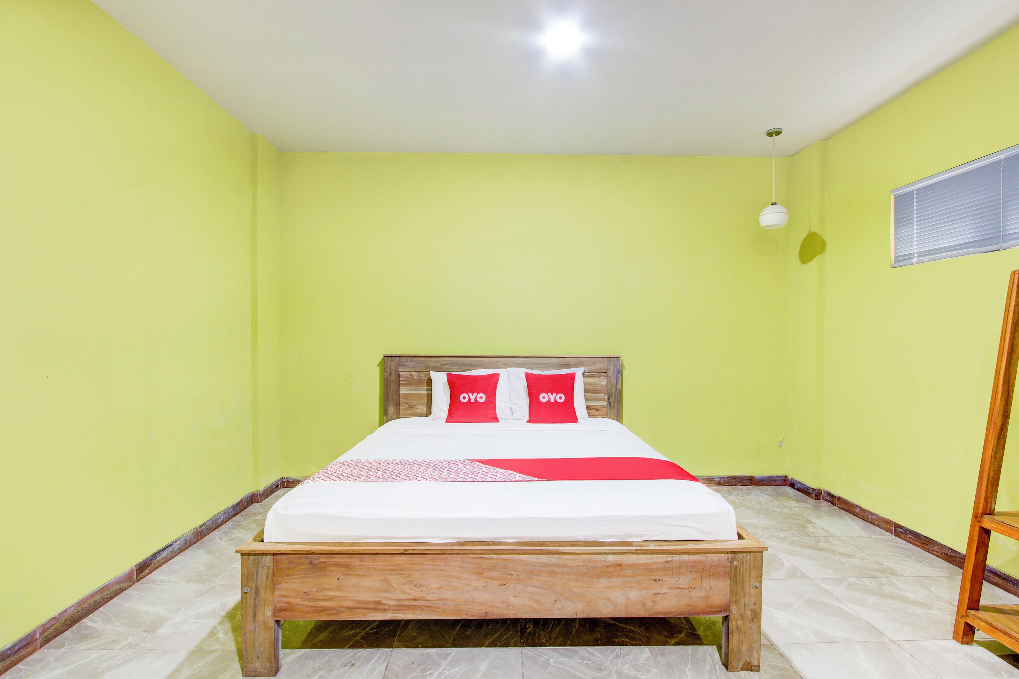 Una habitación con cama de madera, paredes verdes y una lámpara de techo blanca.