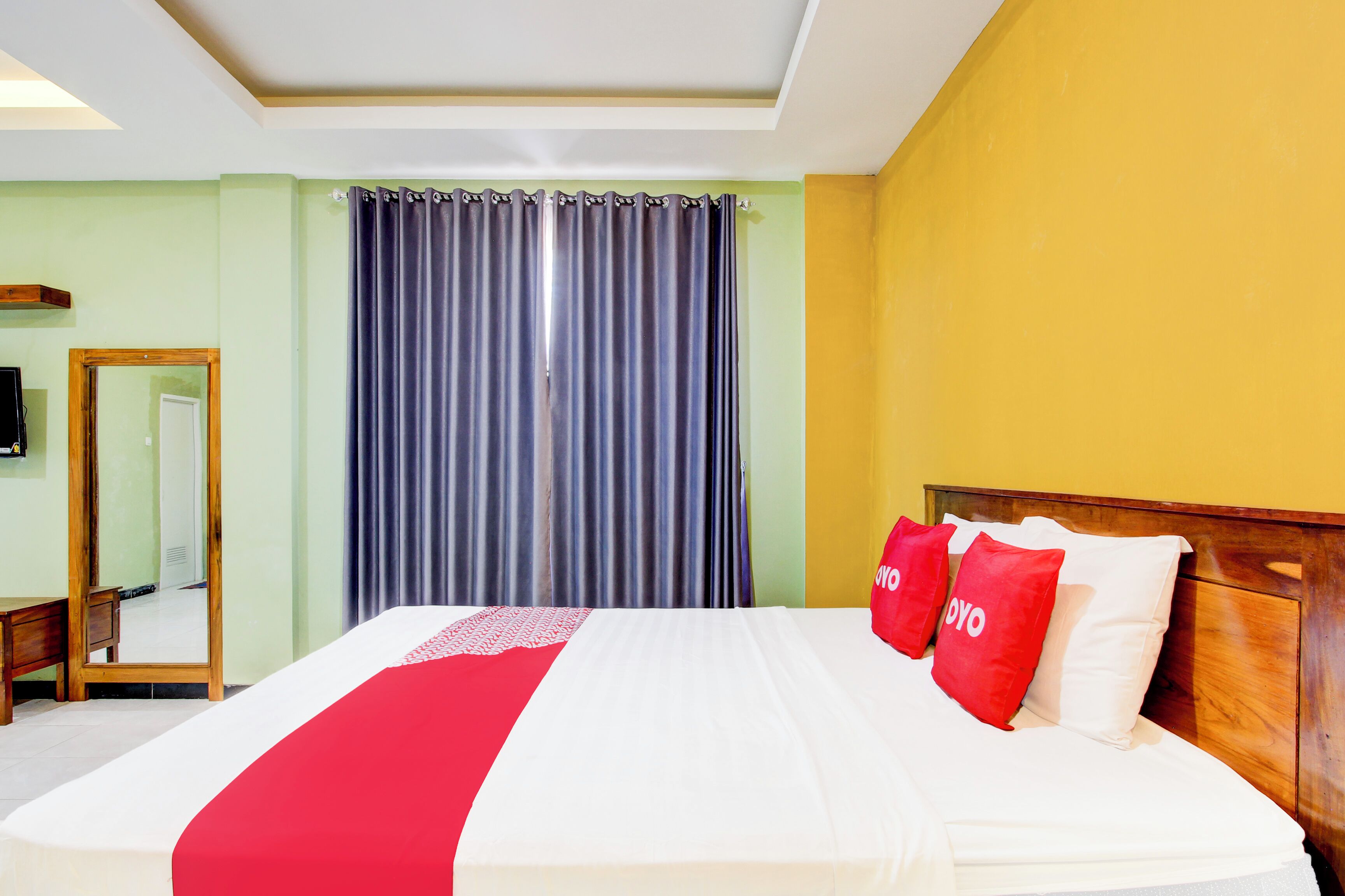 Une chambre d’hôtel avec un grand lit, une tête de lit en bois et un miroir au mur.