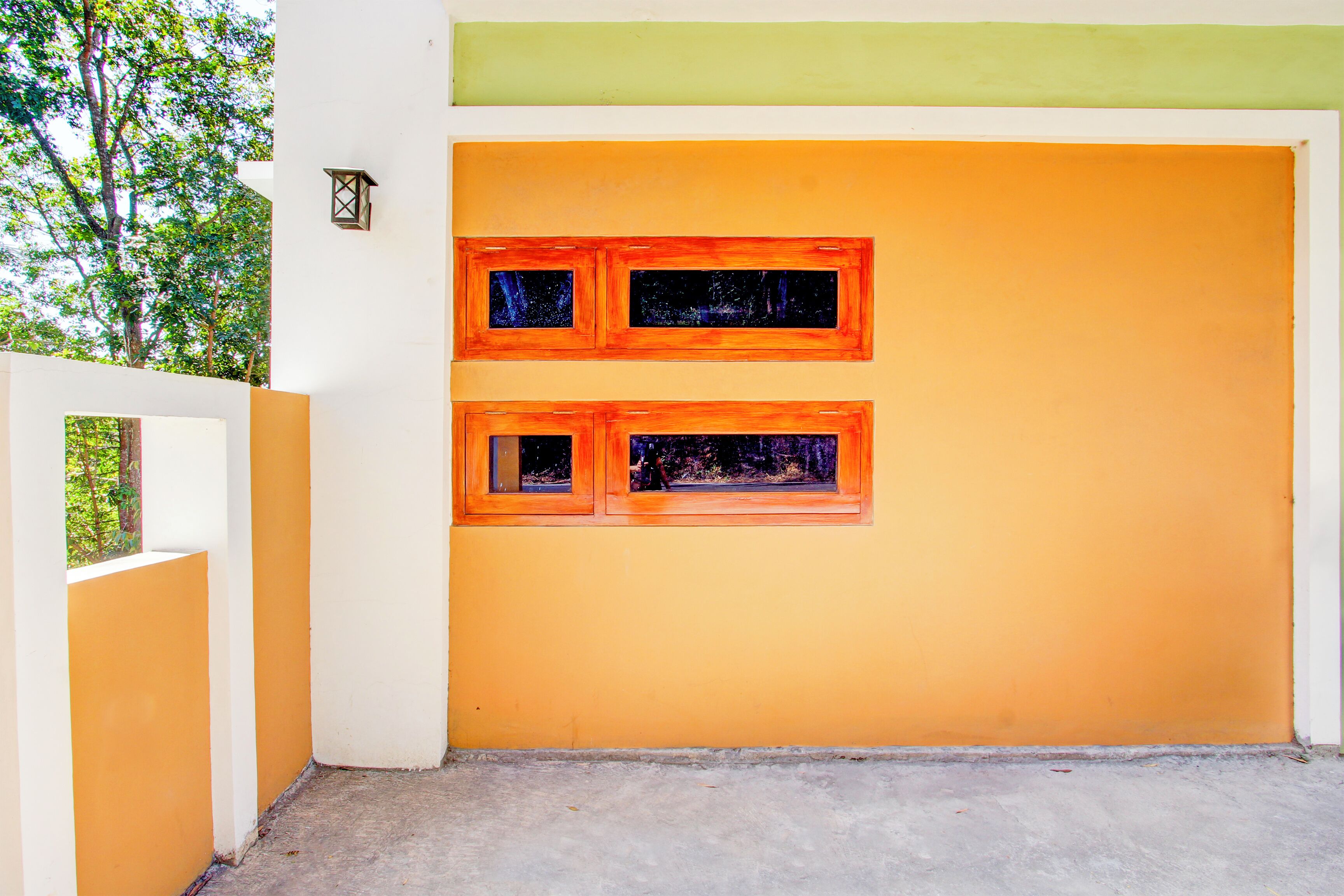 A building with two windows on an orange wall, a white door, and a green upper section.